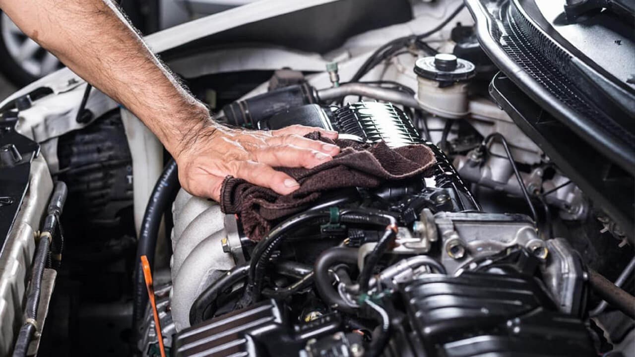 A hand wiping down the engine during a service
